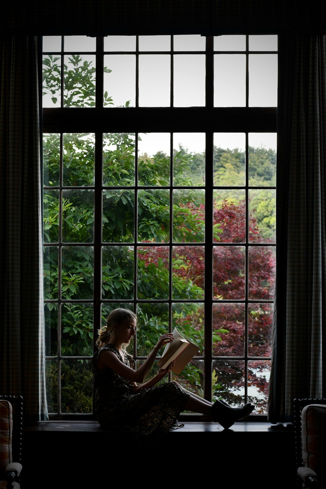 man reading book by window